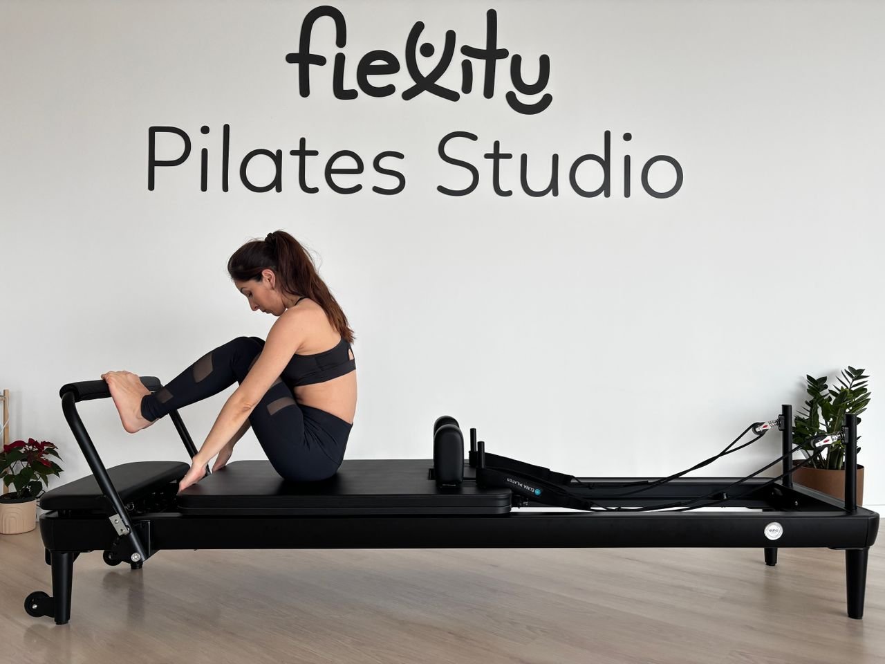 Woman practicing pilates on a reformer in a studio