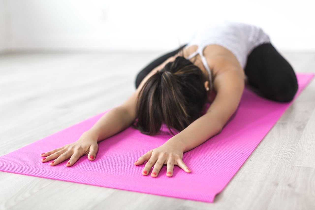 Woman over 40 doing a yoga pose on a mat