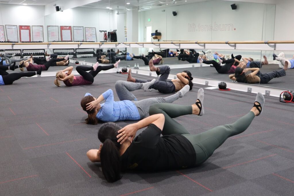 Group of adults in a barre fitness class working on core and lower-body strength