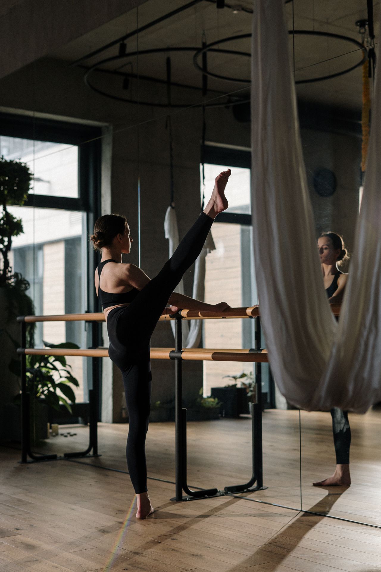 Woman doing barre exercises at the barre in a bright studio with mirrors